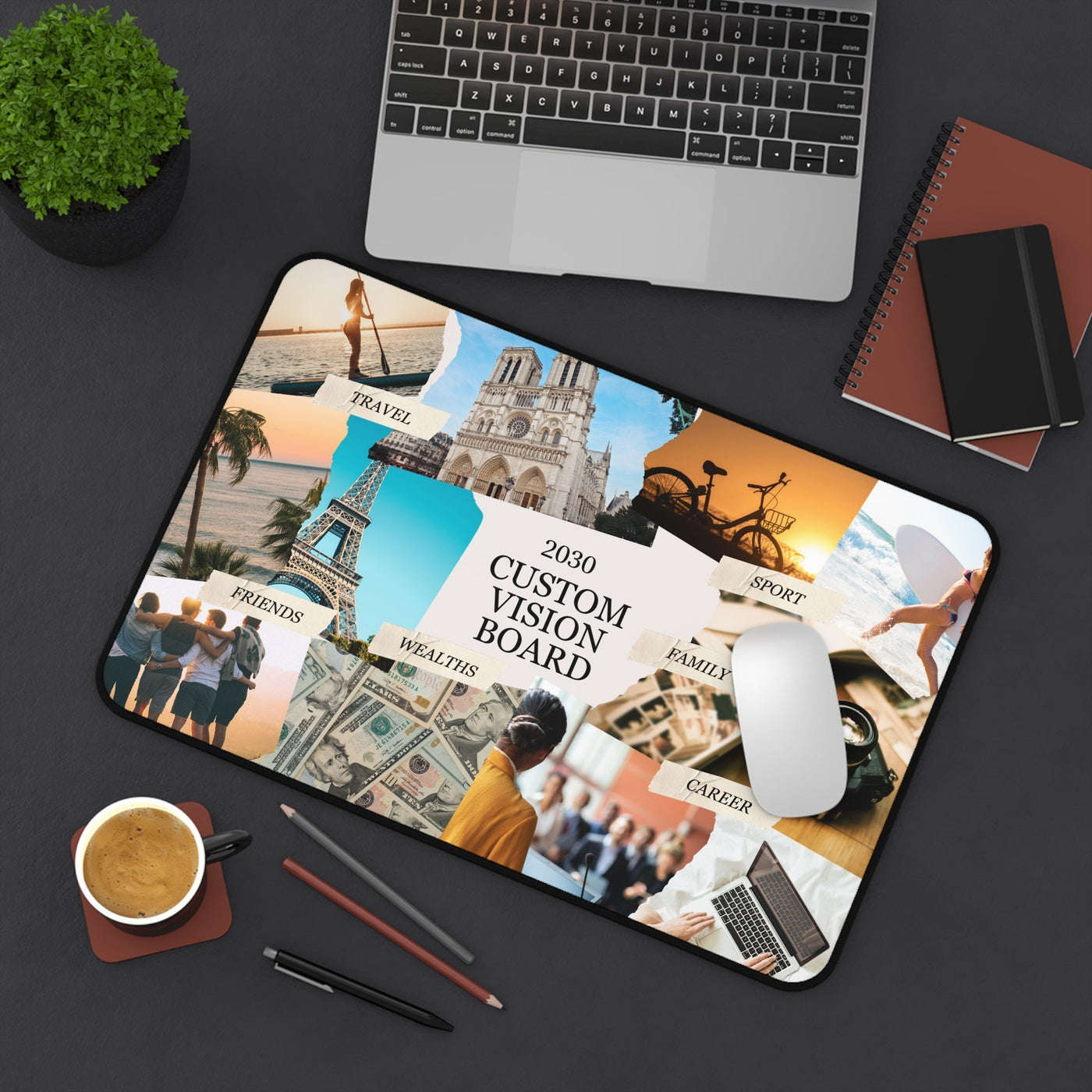 Custom Vision Board Desk Mat with motivational images and words like travel, sport, family, friends, wealth, and career, placed on a black desk with laptop, notebook, mouse, coffee, and pens.
