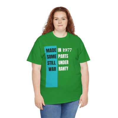 Humorous green t-shirt with "Made In Some Parts Still Under Warranty" slogan in vintage style.