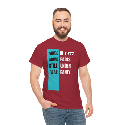 Humorous aging t-shirt with "Made In Some Parts Still Under Warranty" slogan, vintage style.